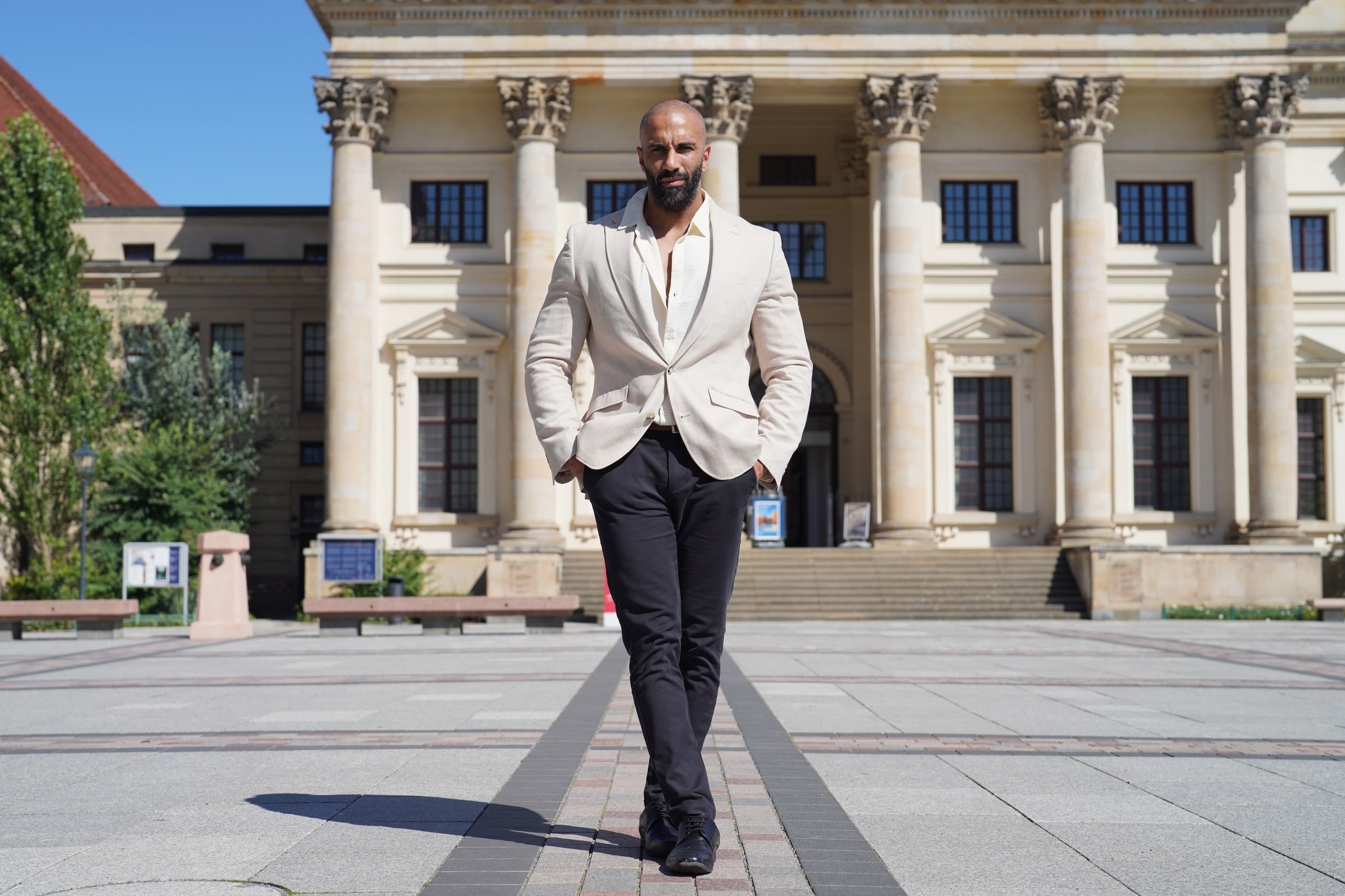 Amer El-Erwadi crossing the Gendarmenmarkt square in morning light, long shadow behind him.