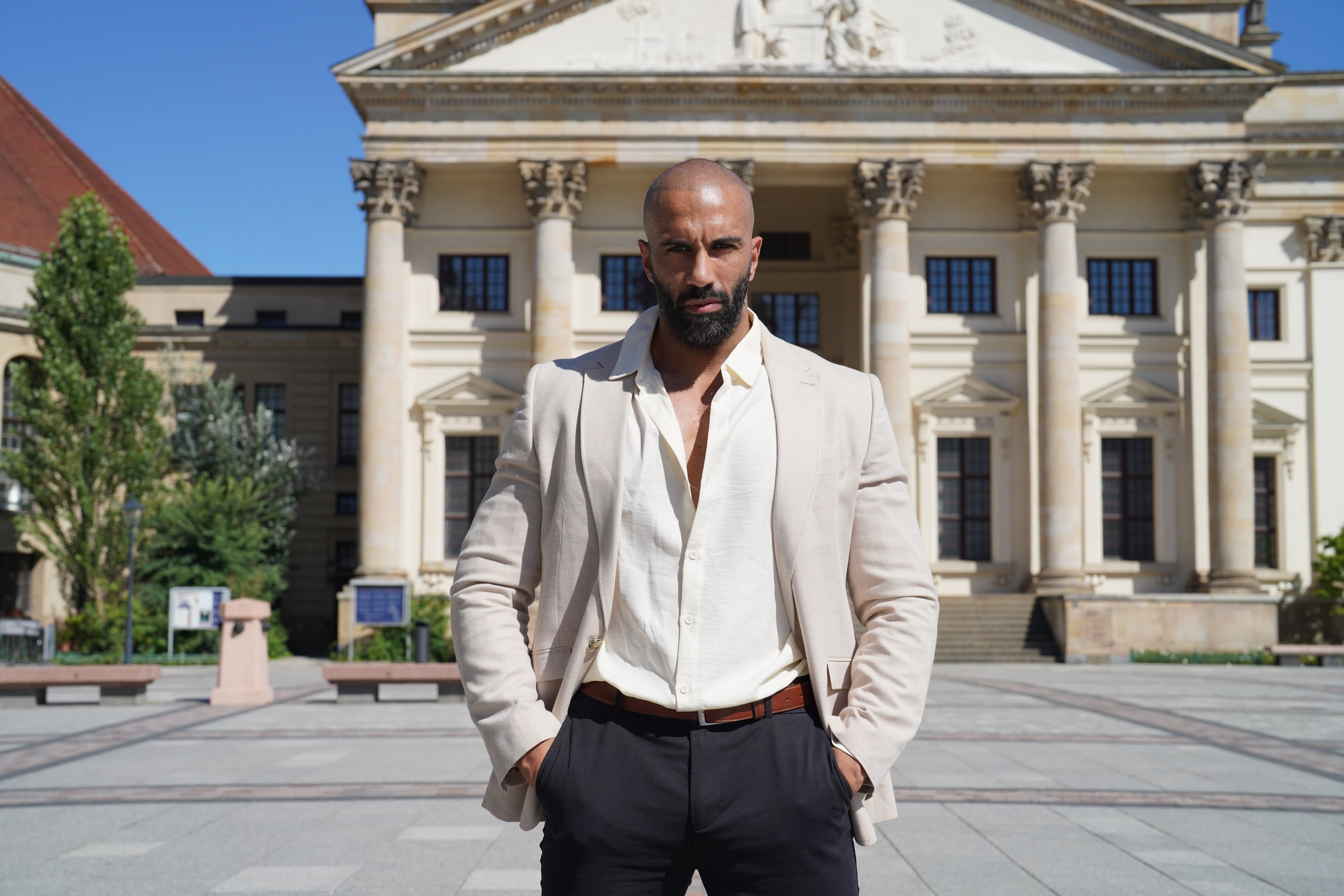 Amer El-Erwadi standing centred before the Konzerthaus colonnade, hands in pockets.