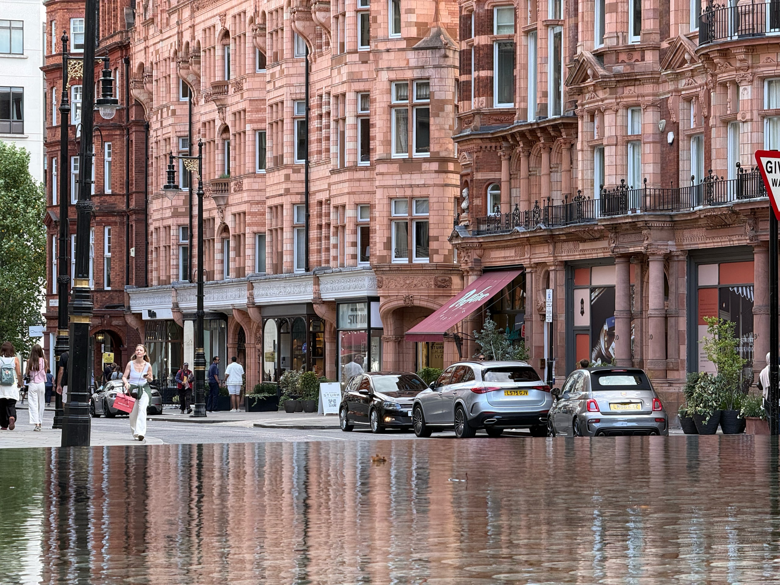 Red brick mansion blocks along a wet Mayfair street.
