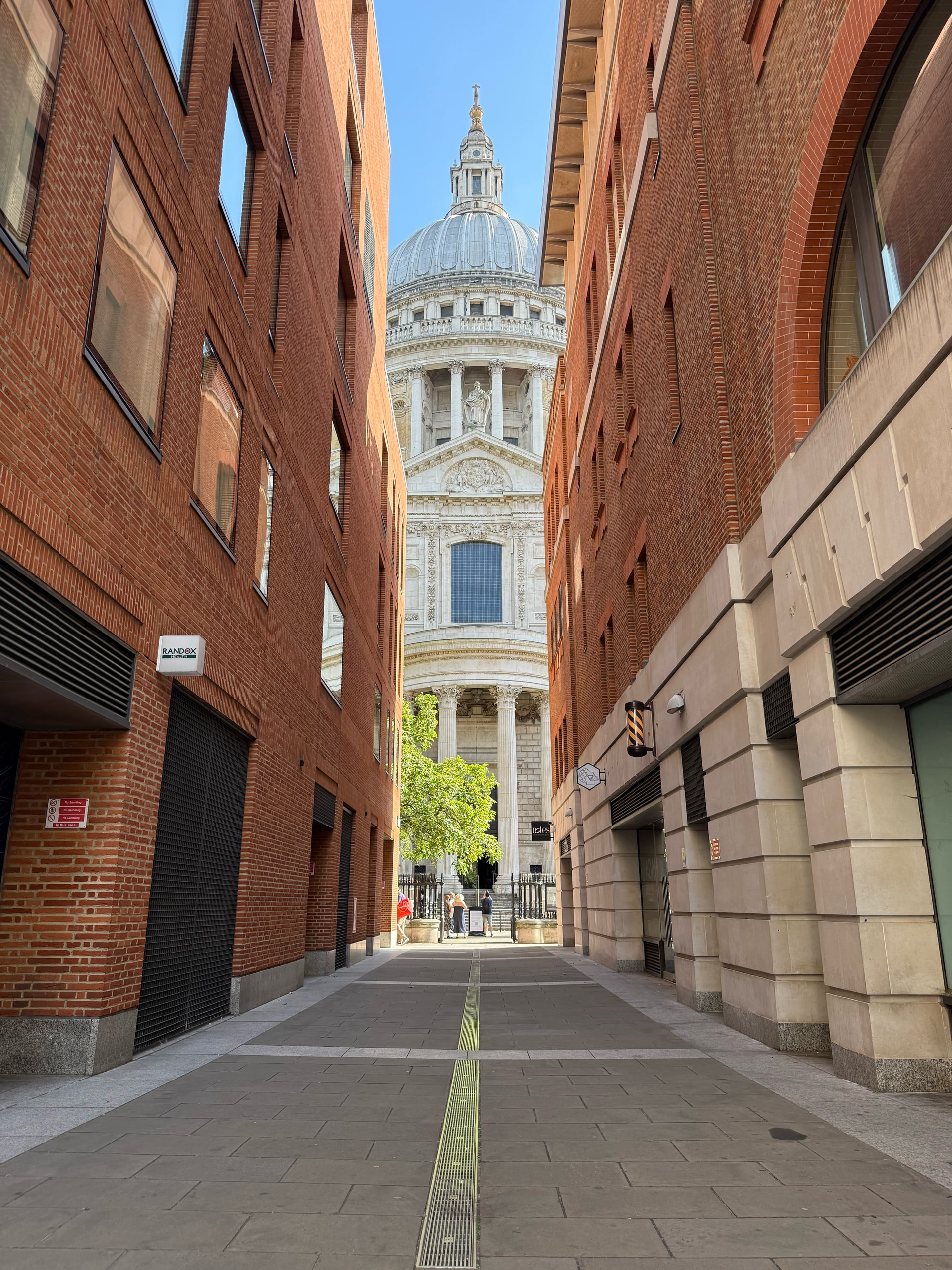 A narrow alley opening onto the dome of St Paul's Cathedral.