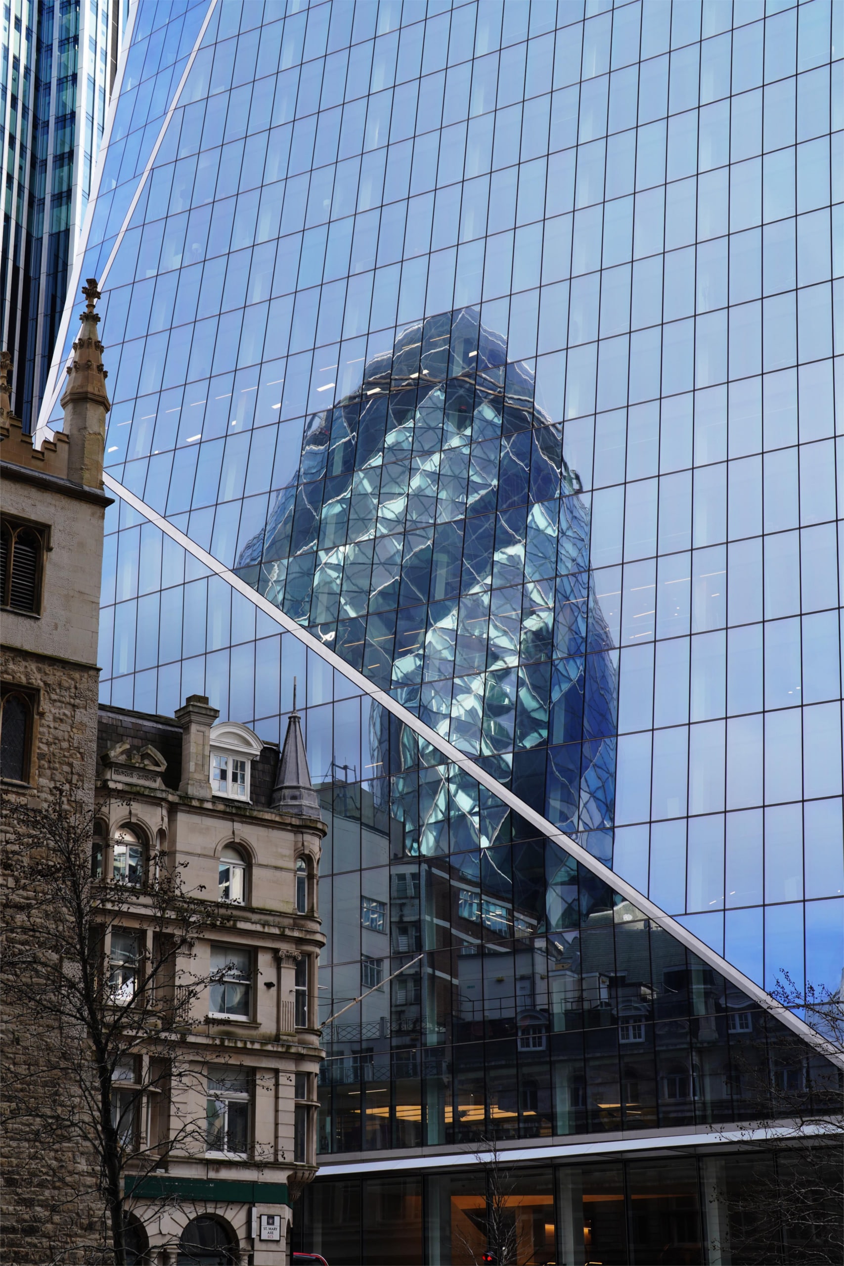 The Gherkin reflected across the glass facade of a neighbouring tower.