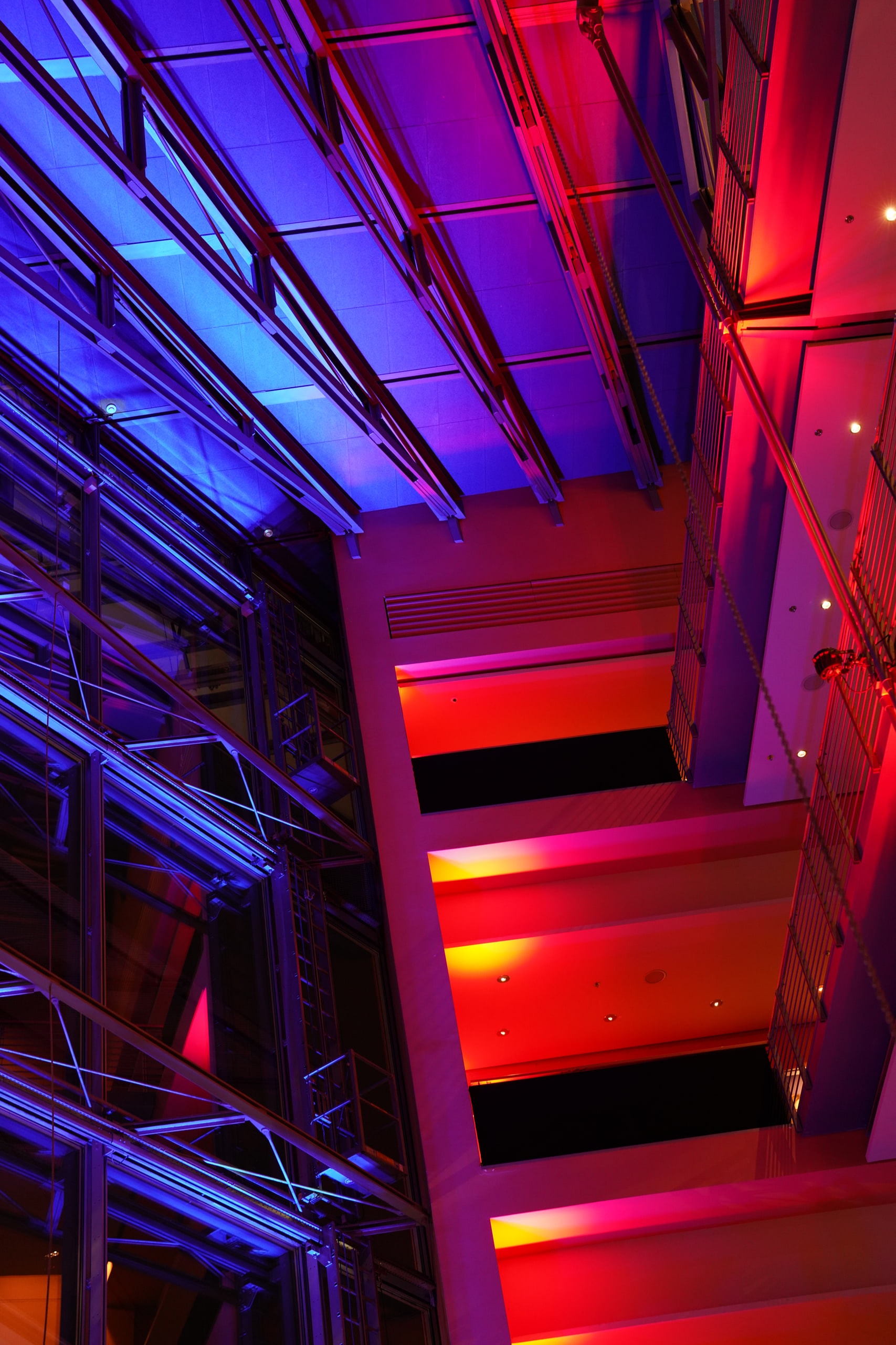 Red and blue light cutting through the glass and steel interior of the Berlinale Palast.