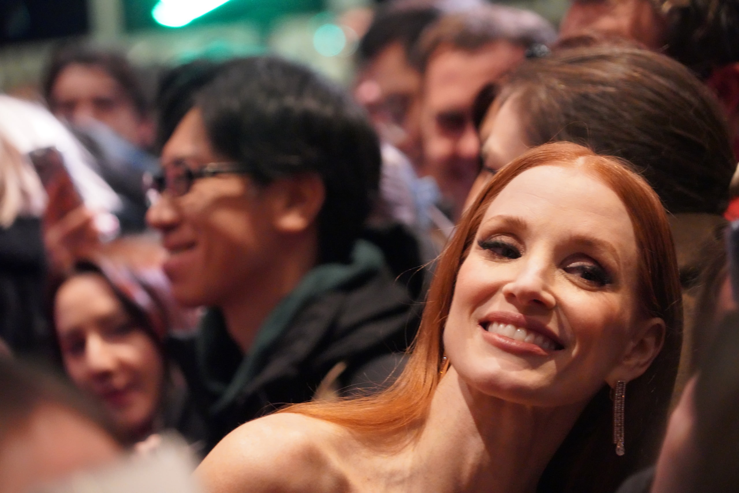 Jessica Chastain smiling in the crowd along the red carpet.