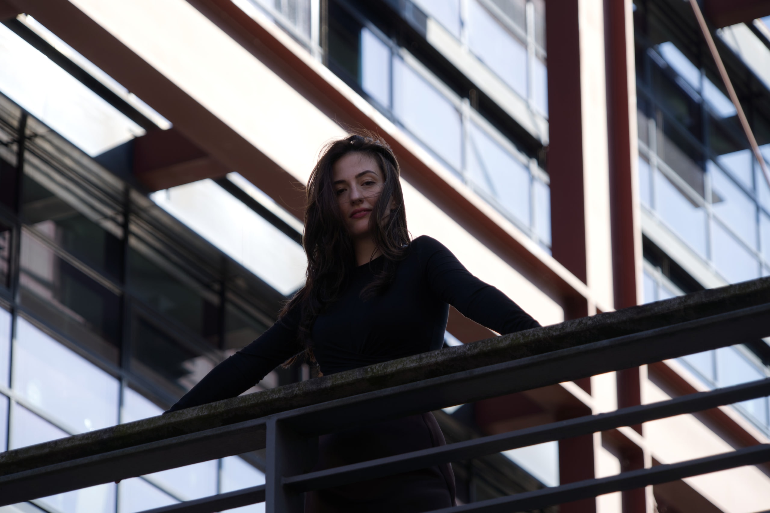 Breshna Hamid Khan seen from below on a footbridge, framed by railings and diagonal beams.