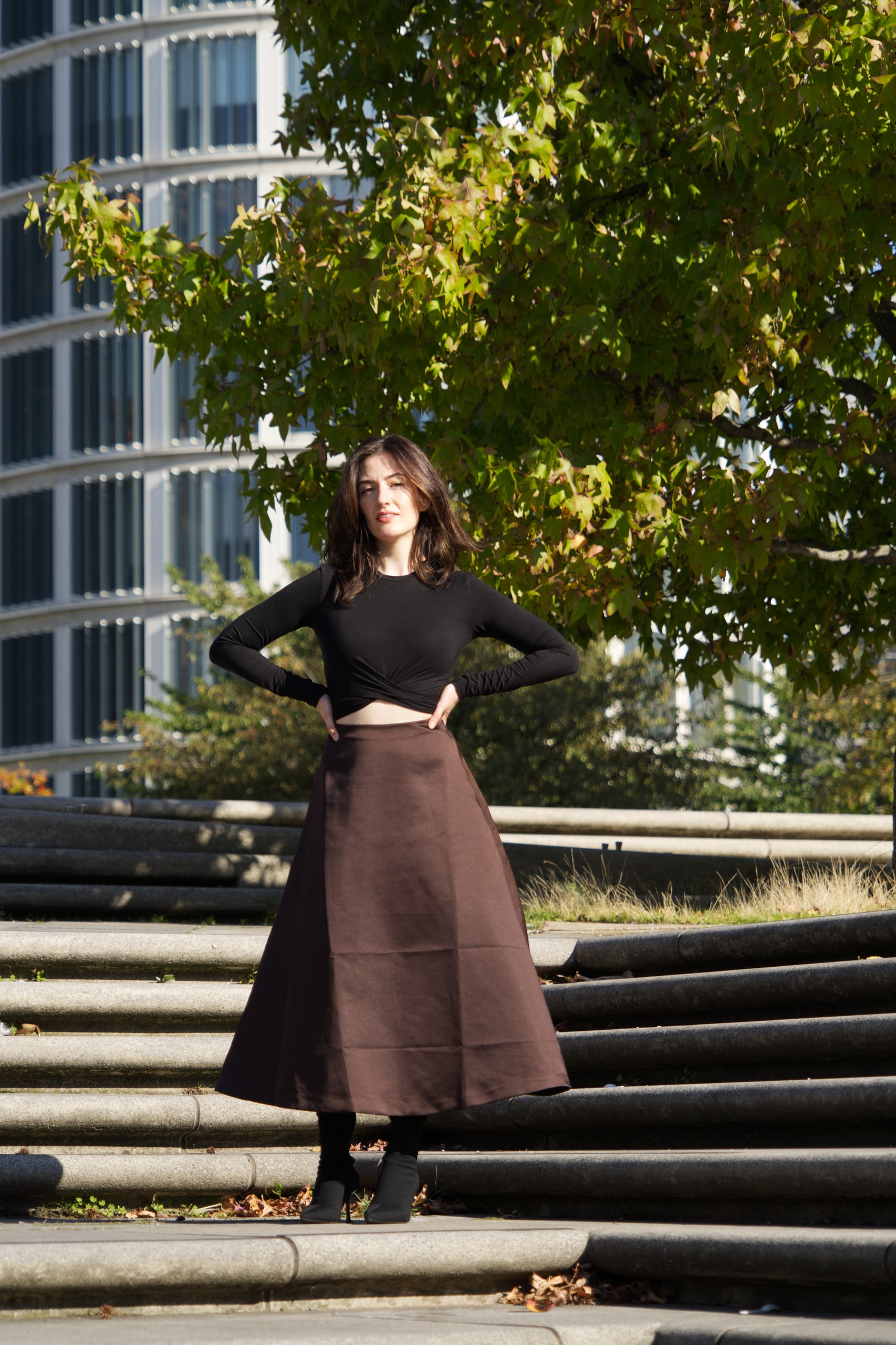 Full-length portrait of Breshna Hamid Khan on sunlit steps, hands on her hips.