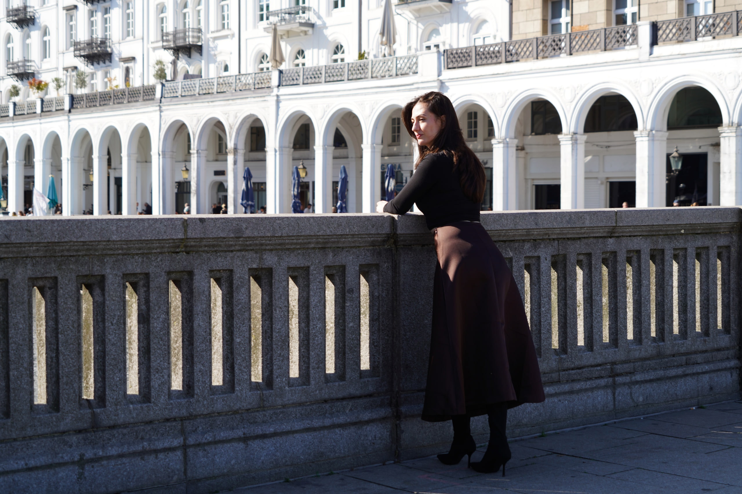 Breshna Hamid Khan beside a stone balustrade with white arcades across the water.