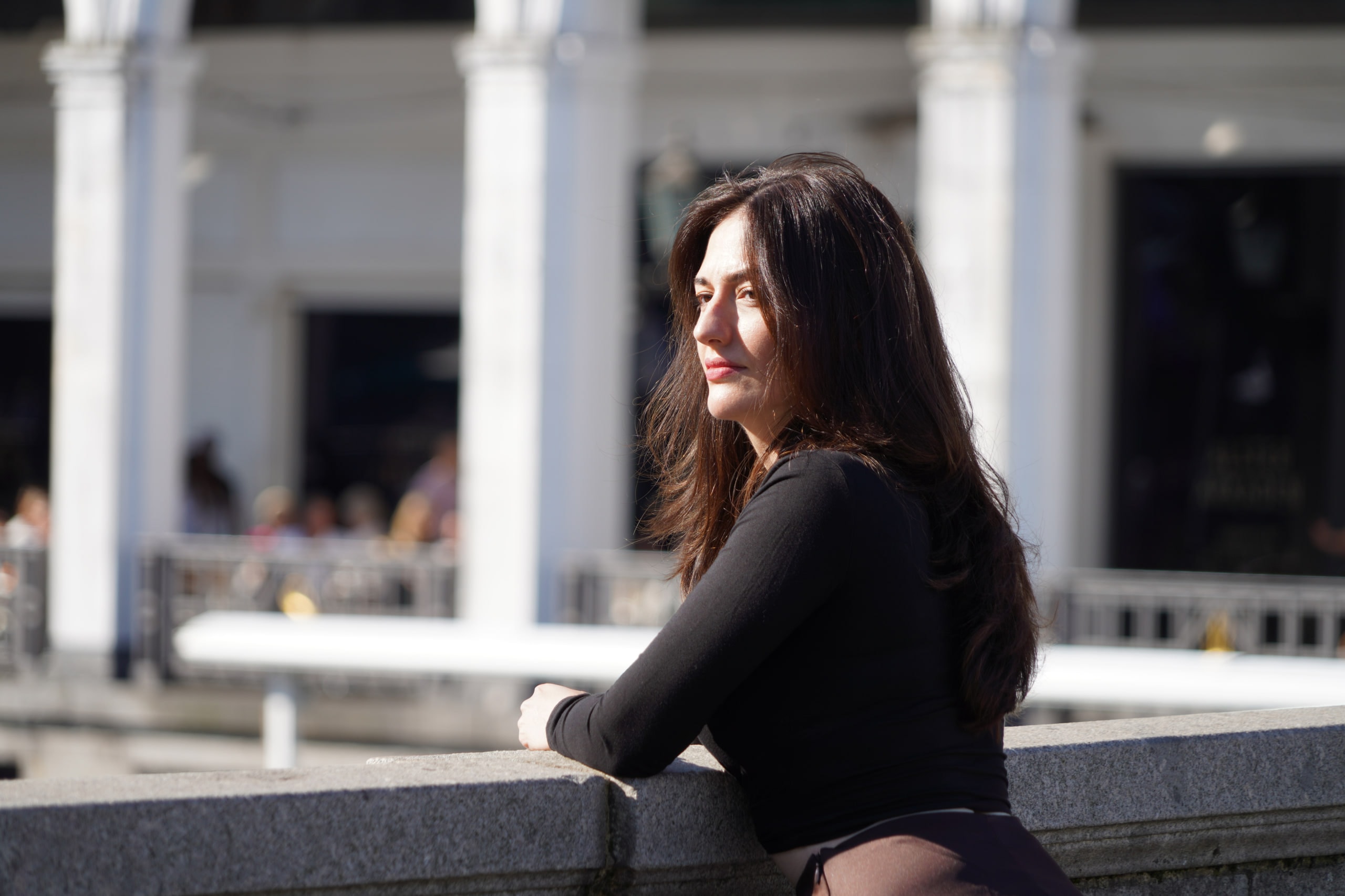Breshna Hamid Khan in profile beside a stone balustrade, white arcades behind her.
