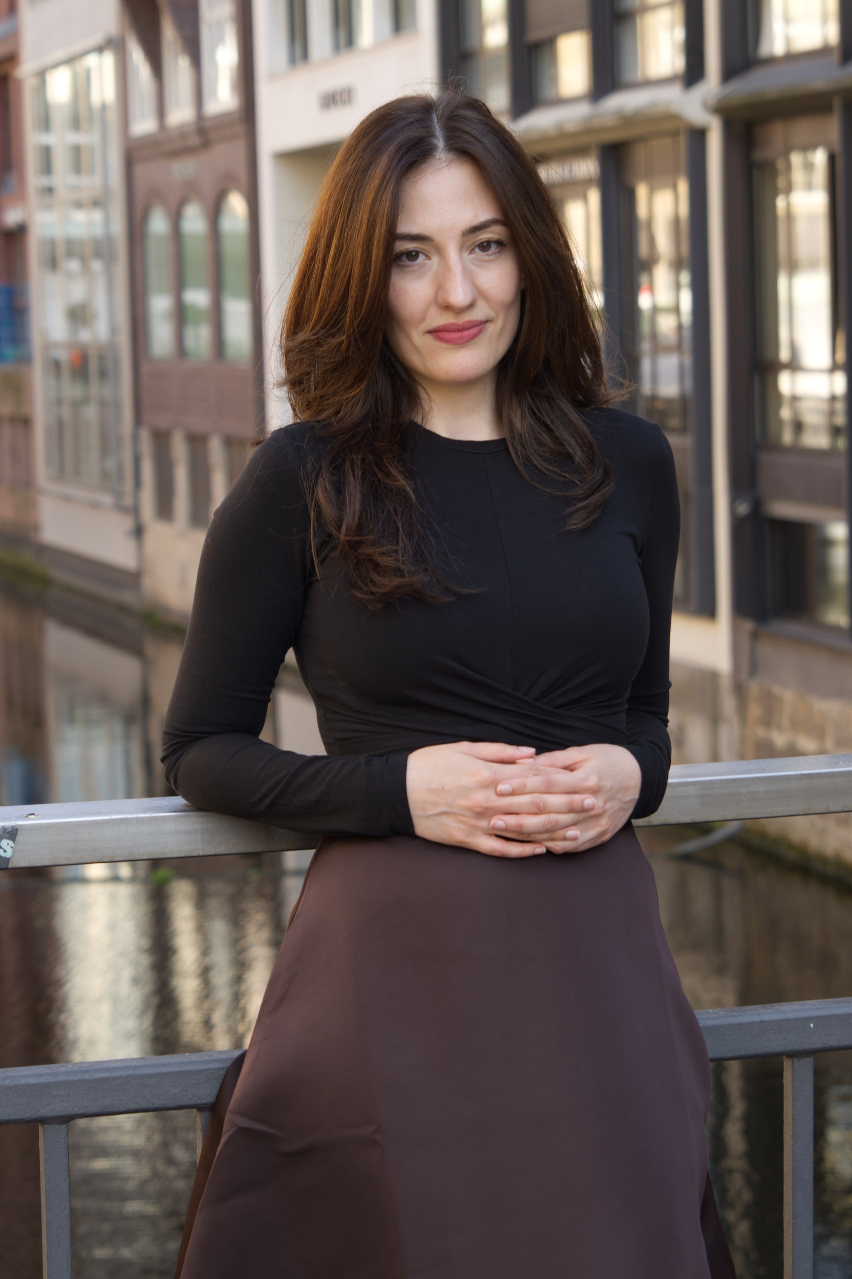 Breshna Hamid Khan standing by a railing with Hamburg buildings behind her.