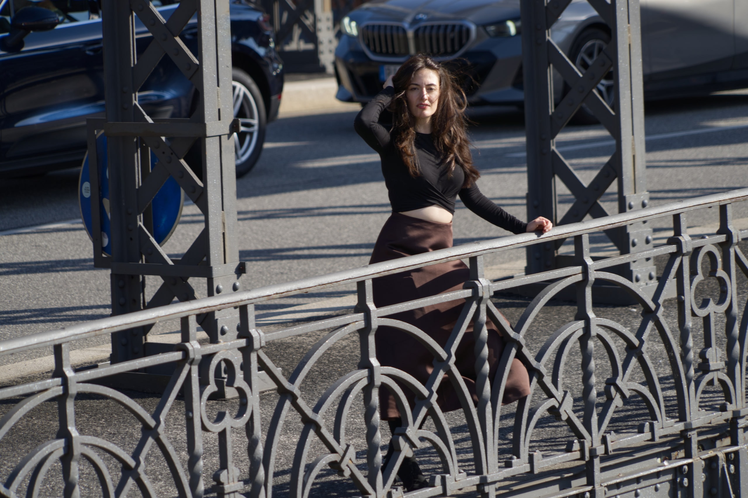 Breshna Hamid Khan framed by the iron beams and decorative railing of a Hamburg bridge.