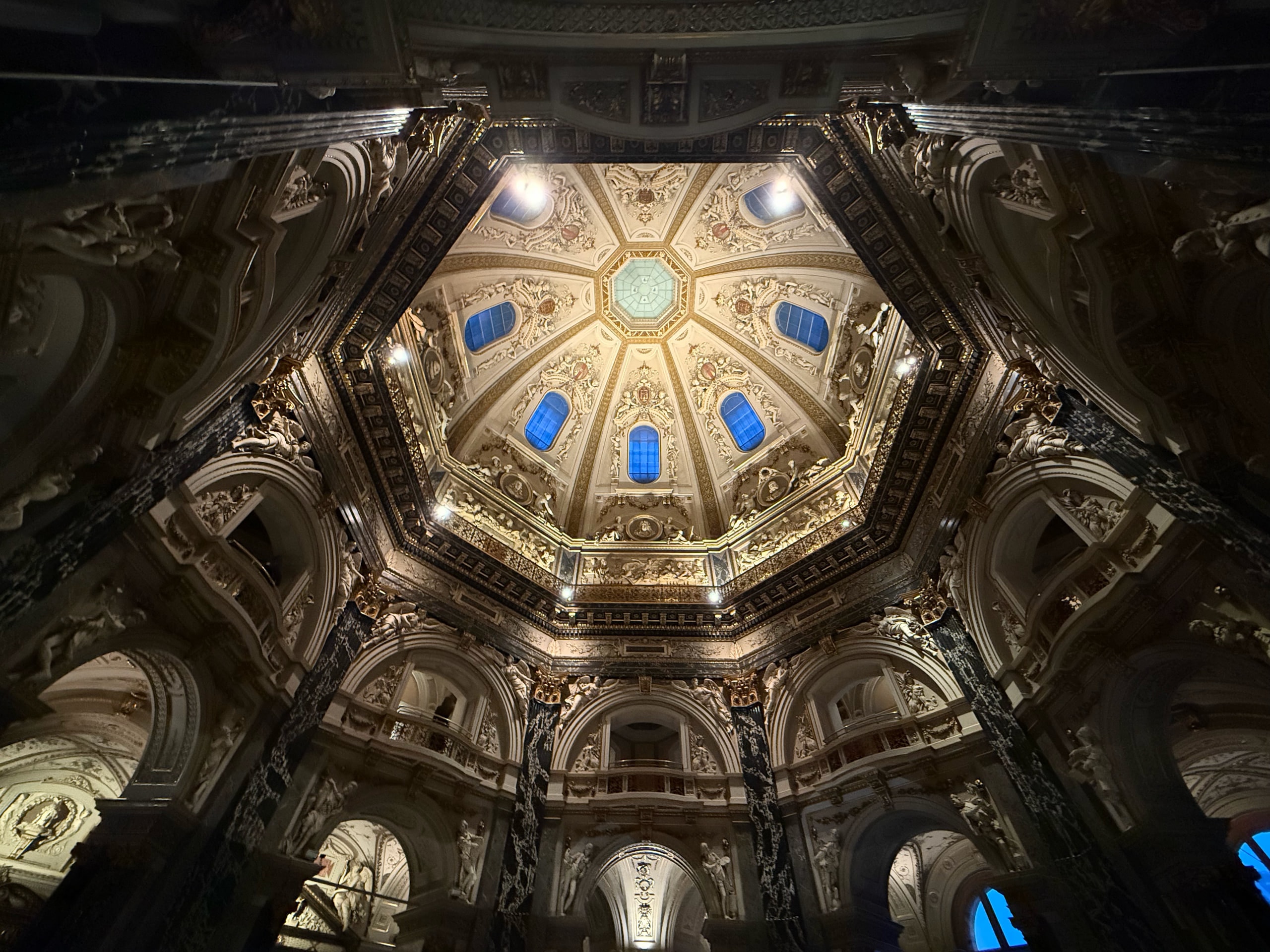 Looking upward into the illuminated octagonal dome of the Kunsthistorisches Museum.