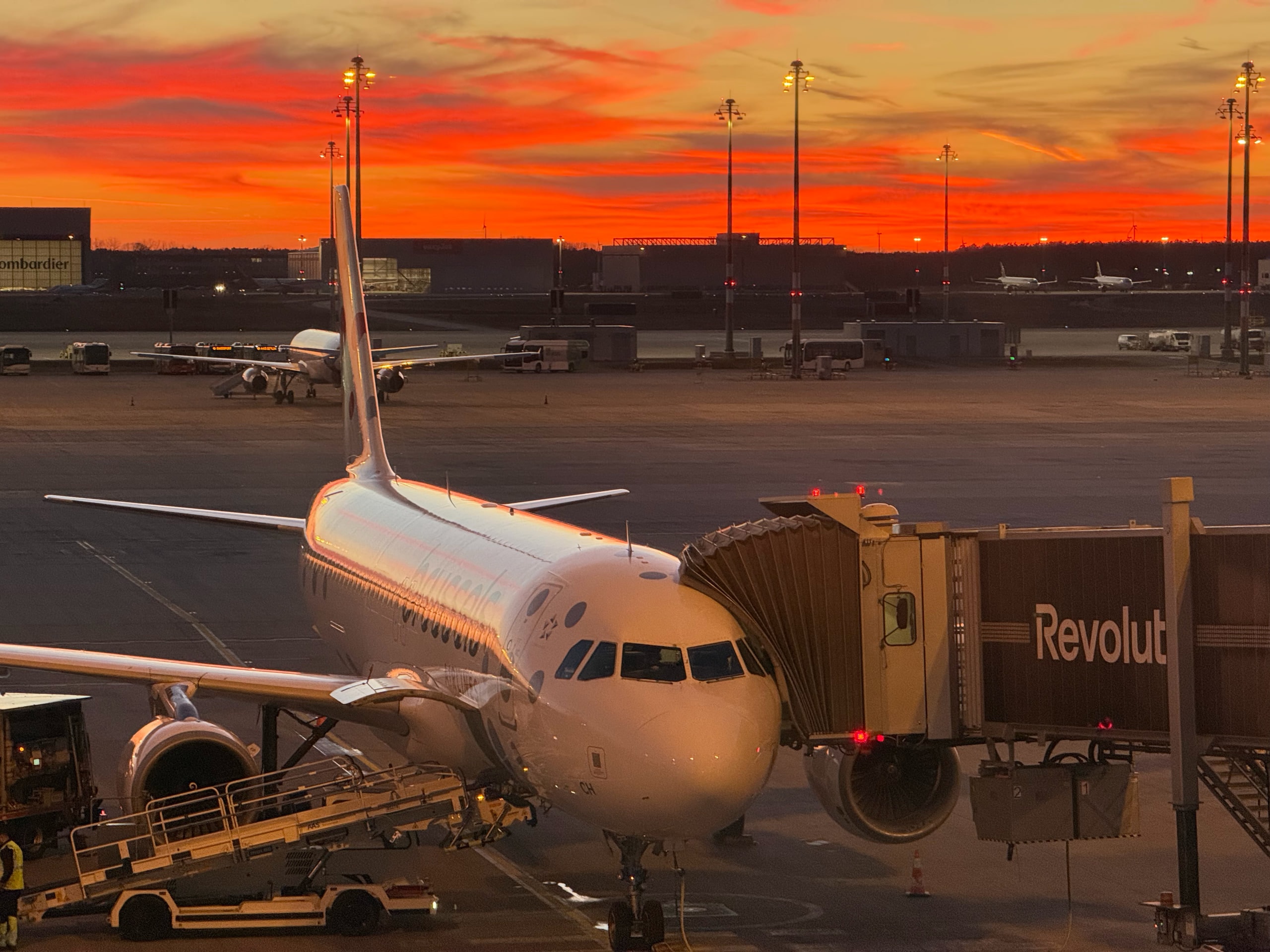 An airliner at a gate under a red-orange sunset.