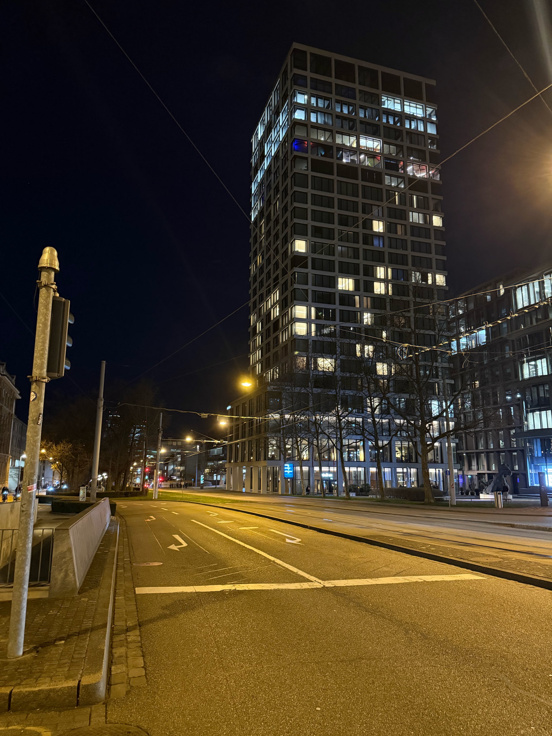 A glass tower seen between city walls at night.