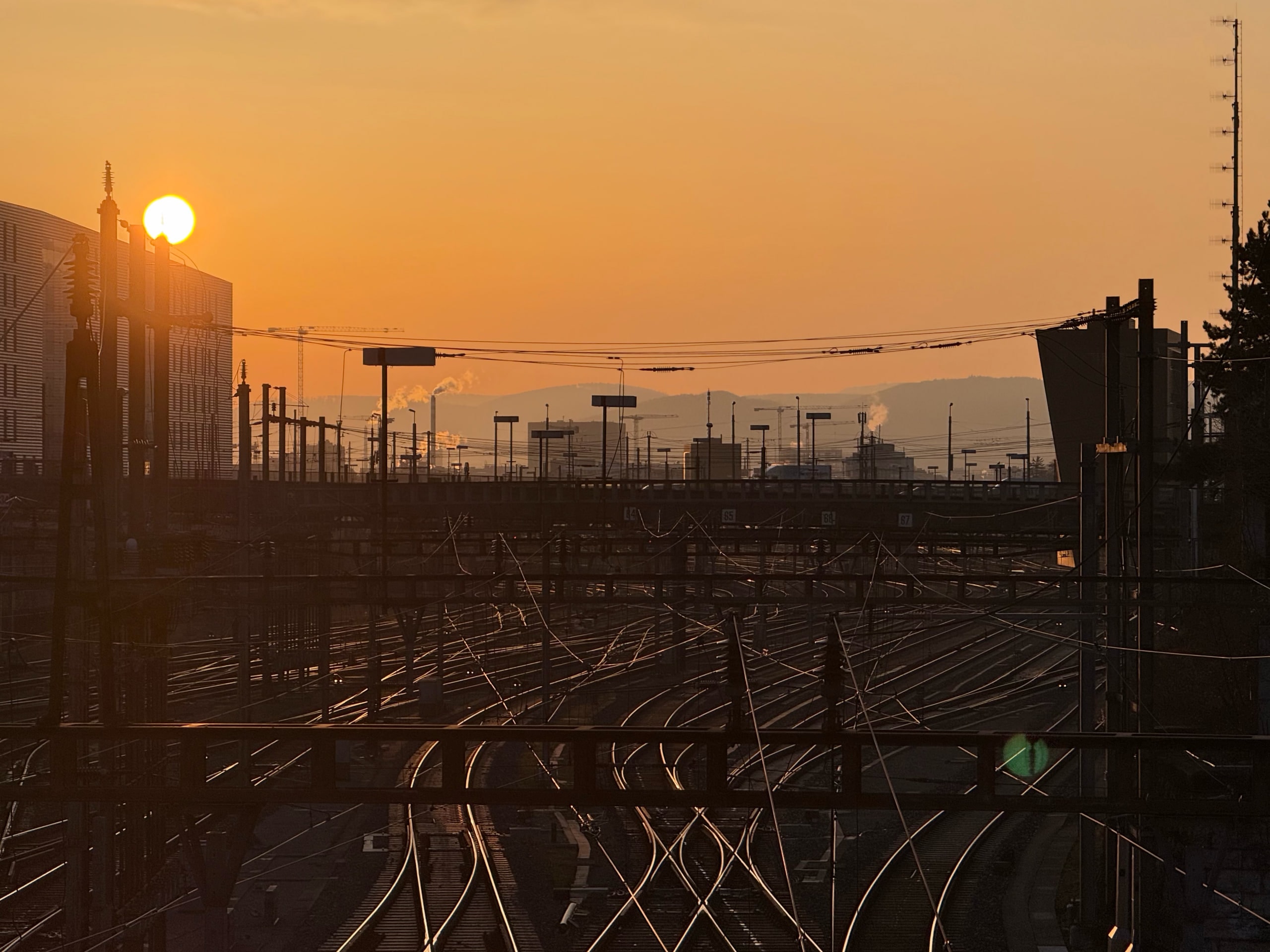 Railway tracks converging beneath a pale sunrise.