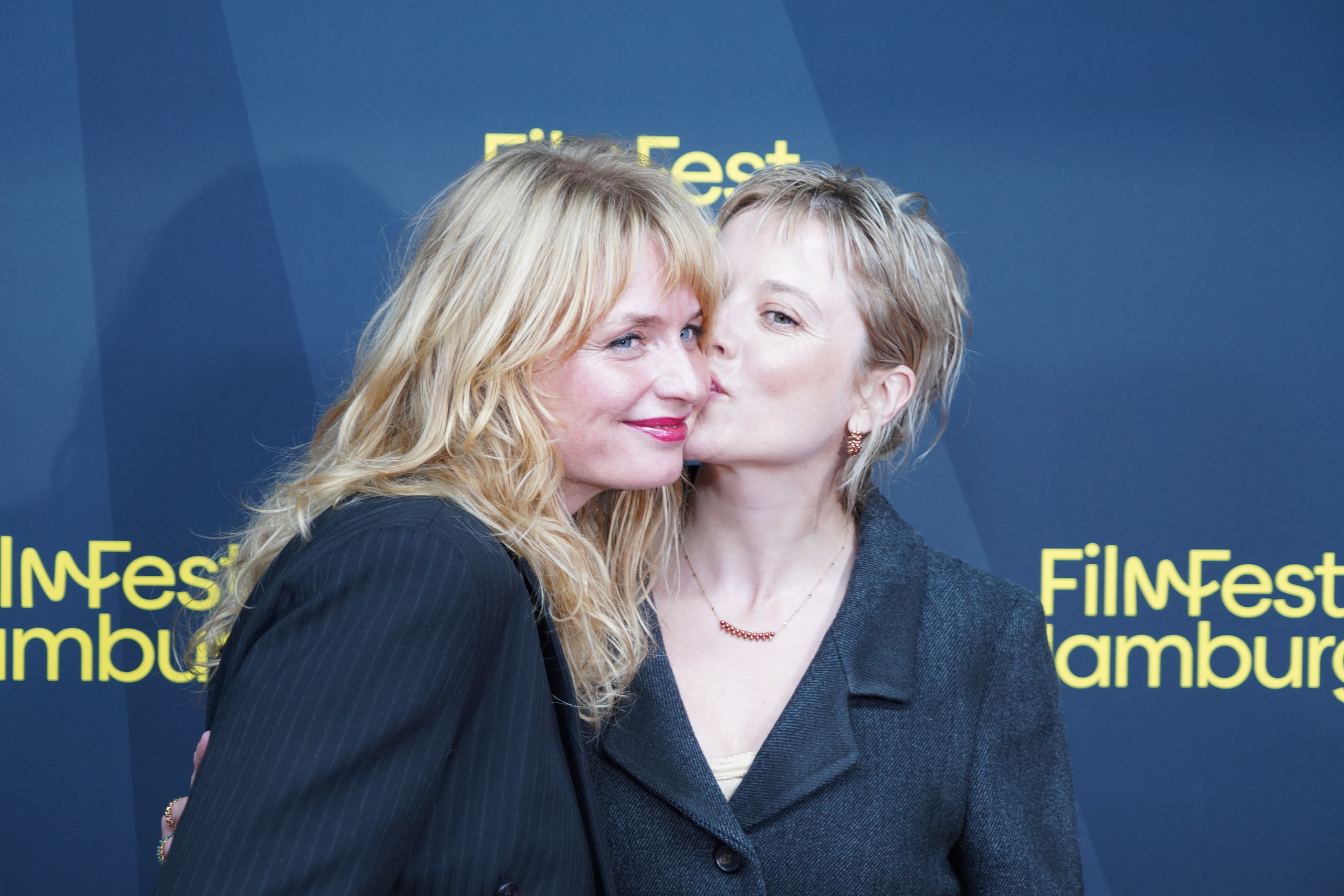 Two members of the Kinder der Sonne team sharing a kiss on the cheek on the red carpet.