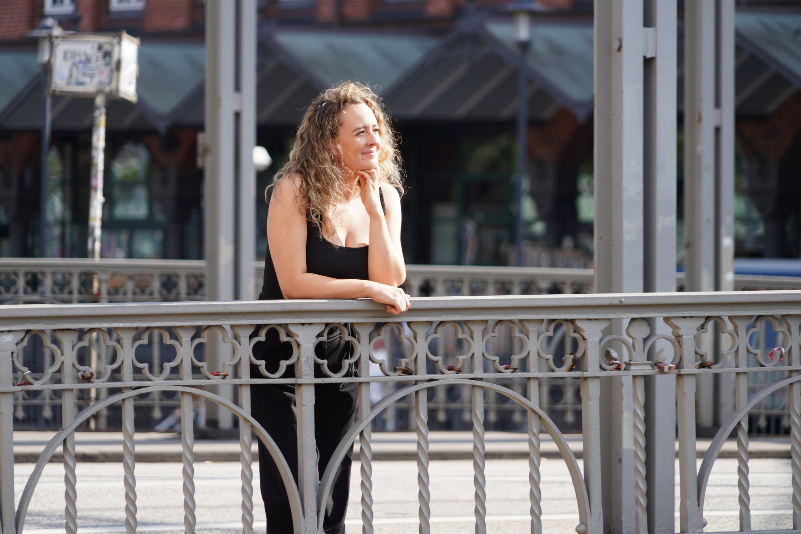 Larissa Kählert looking to one side from behind an ornate iron bridge railing in Hamburg.