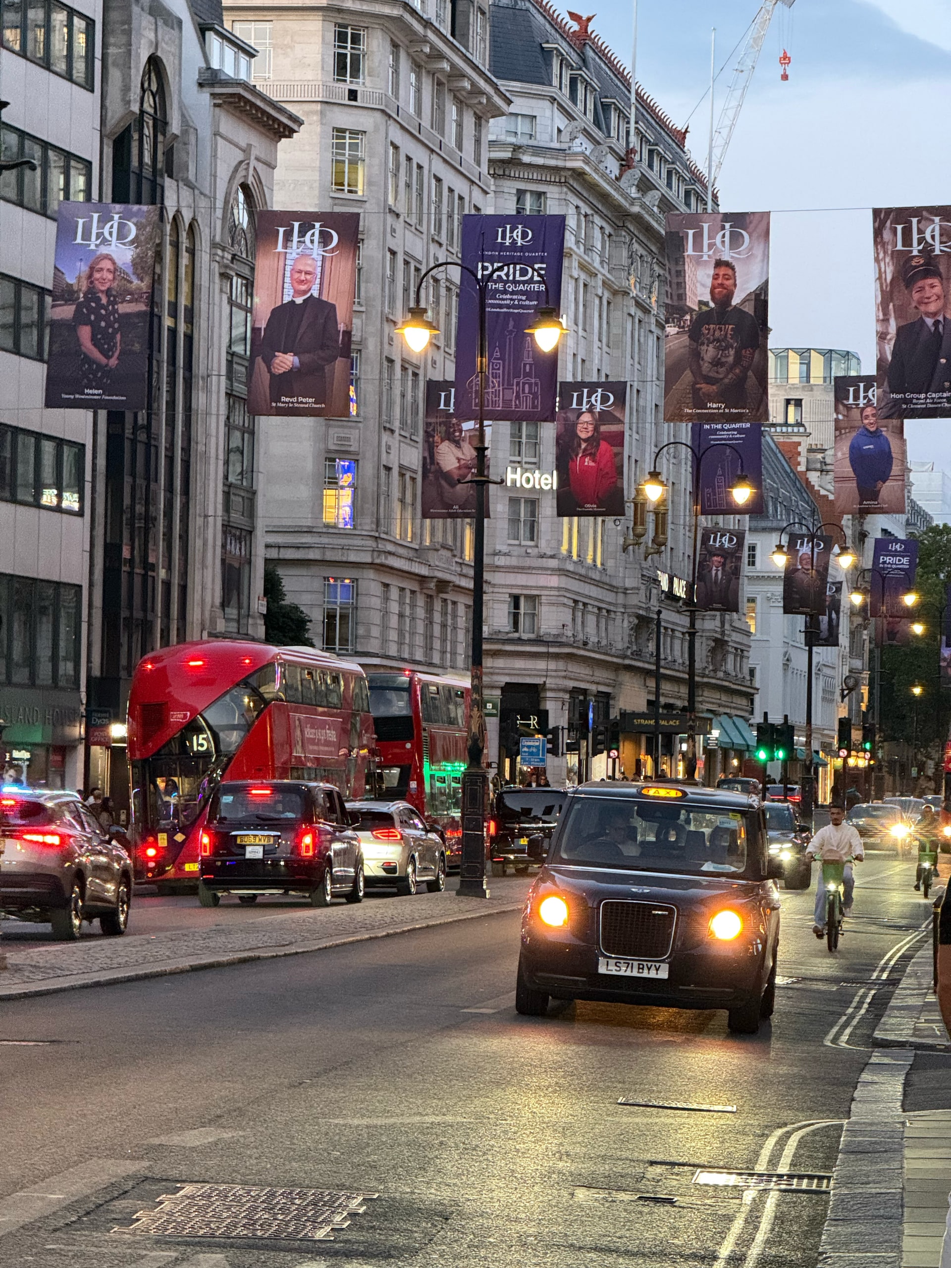 Traffic and lit storefronts along Charing Cross Road at dusk.