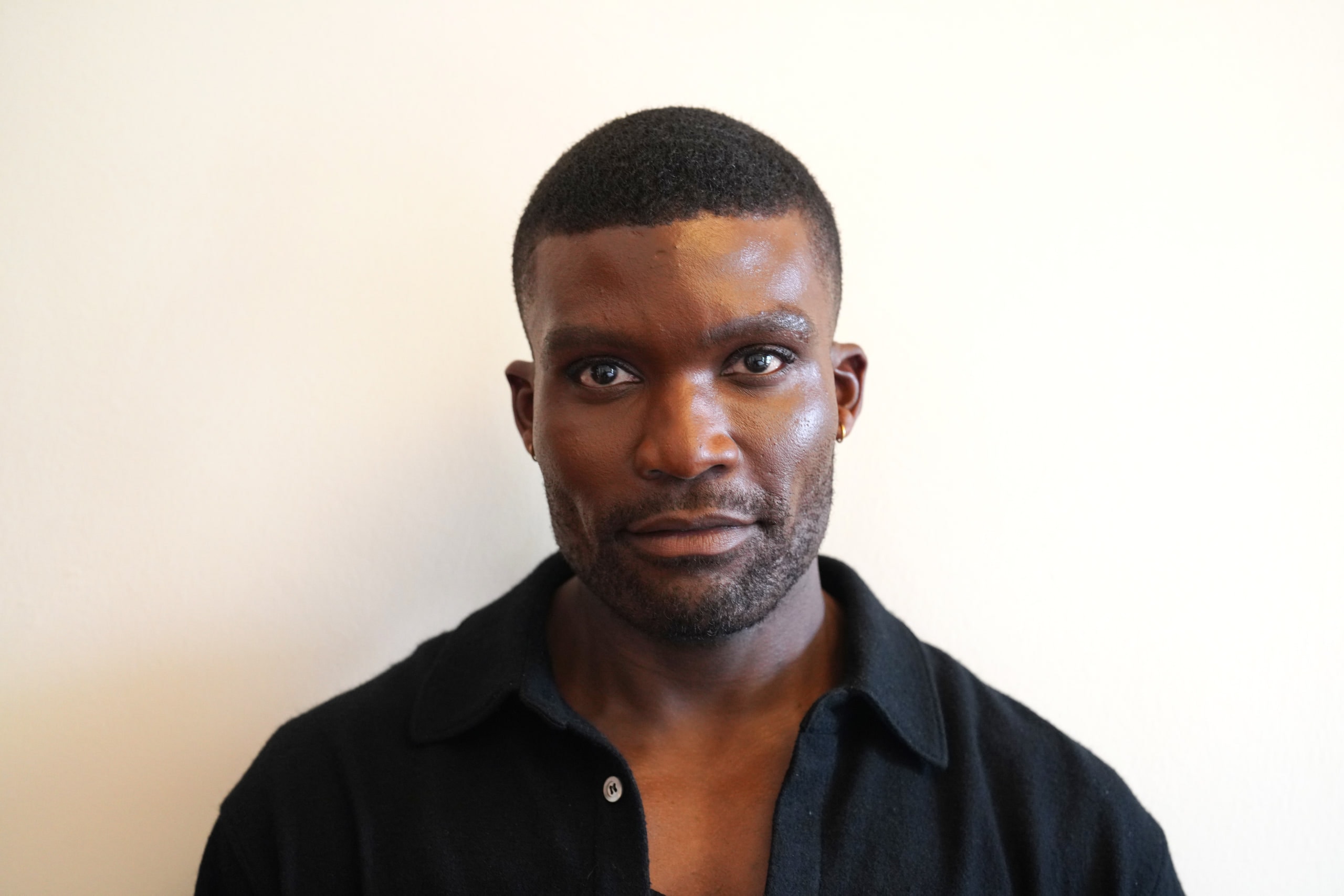 Michael Solomon facing the camera in a black shirt against a pale wall.