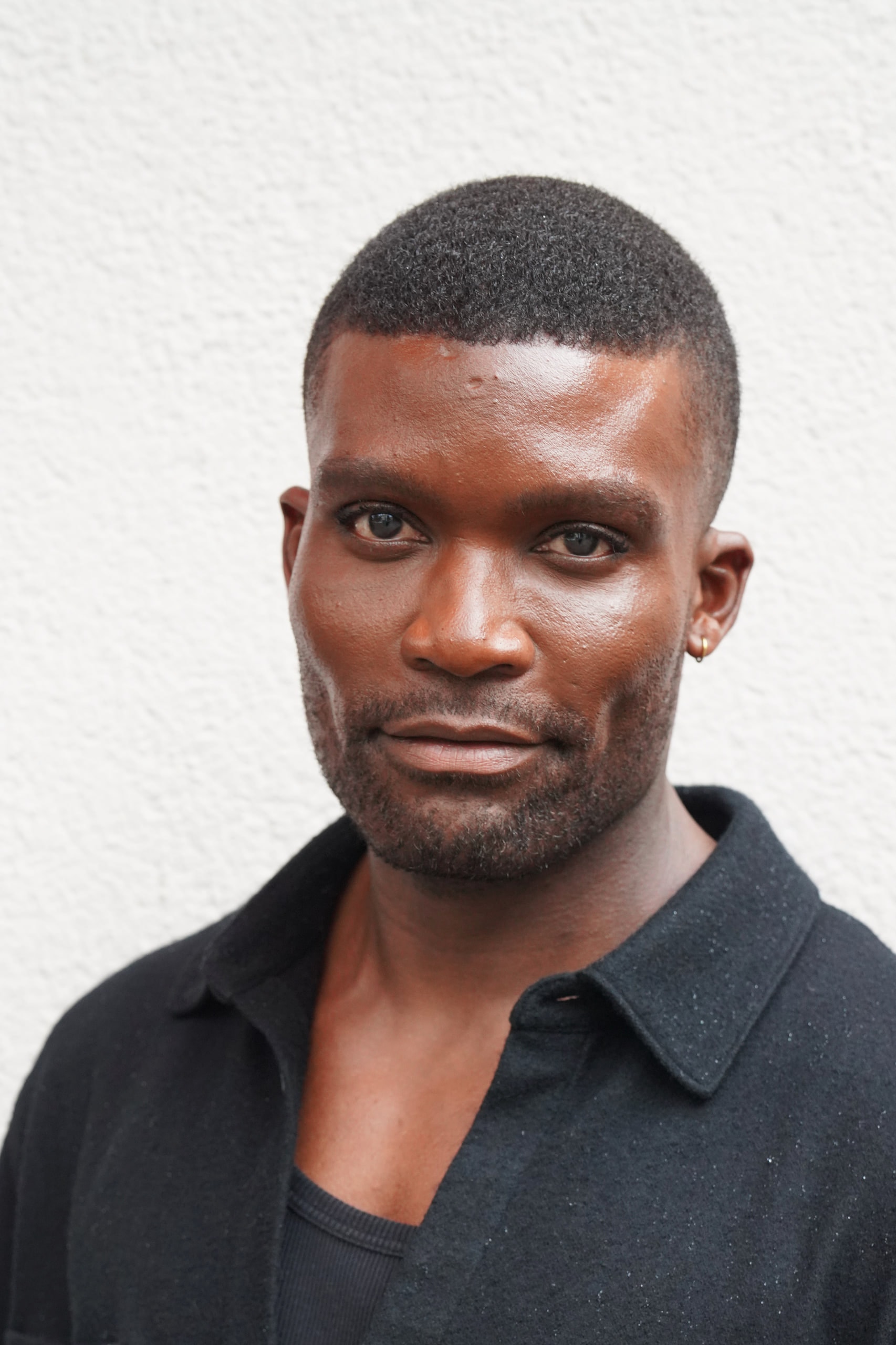 Close vertical portrait of Michael Solomon in a black shirt against a textured white wall.