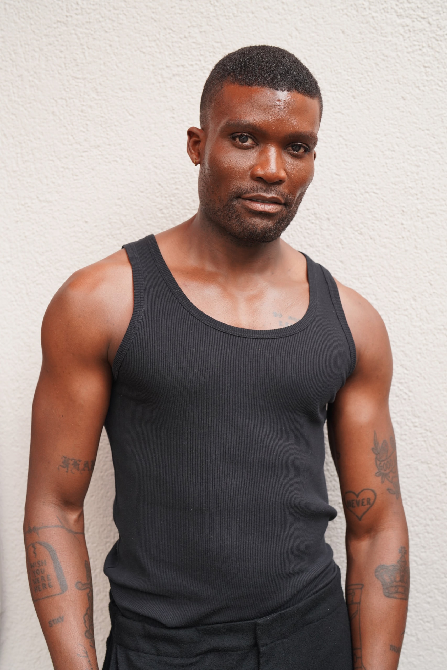 Michael Solomon standing in a black vest against a textured white wall.