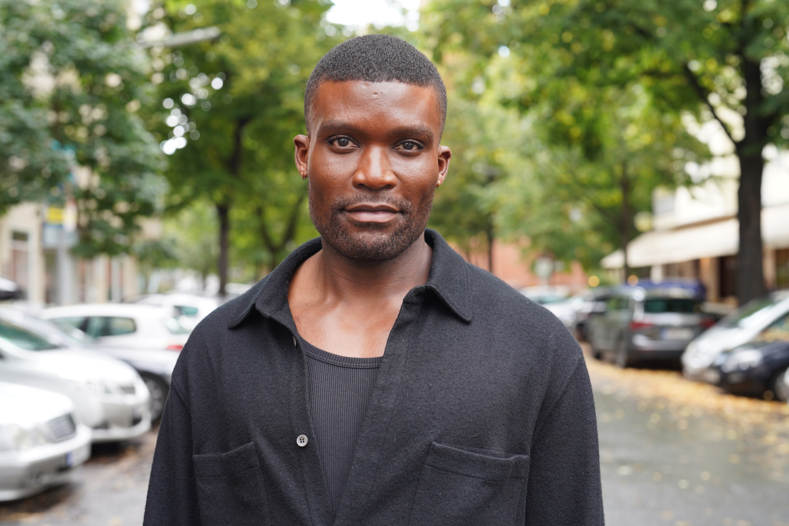 Michael Solomon in a black shirt on a tree-lined Berlin street.