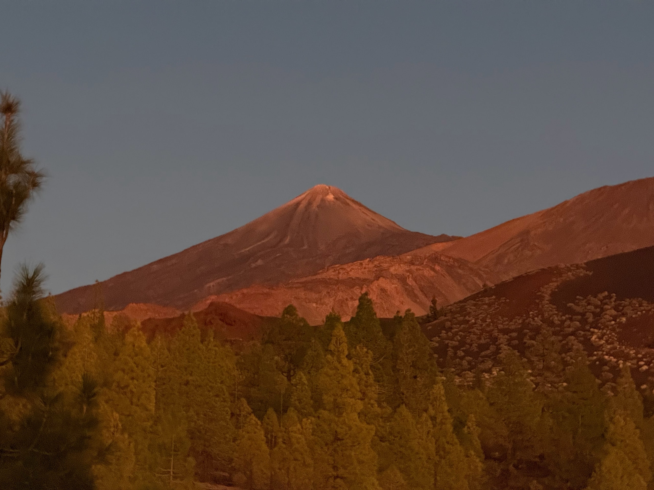 Mount Teide and a neighbouring ridge seen through warm evening haze.