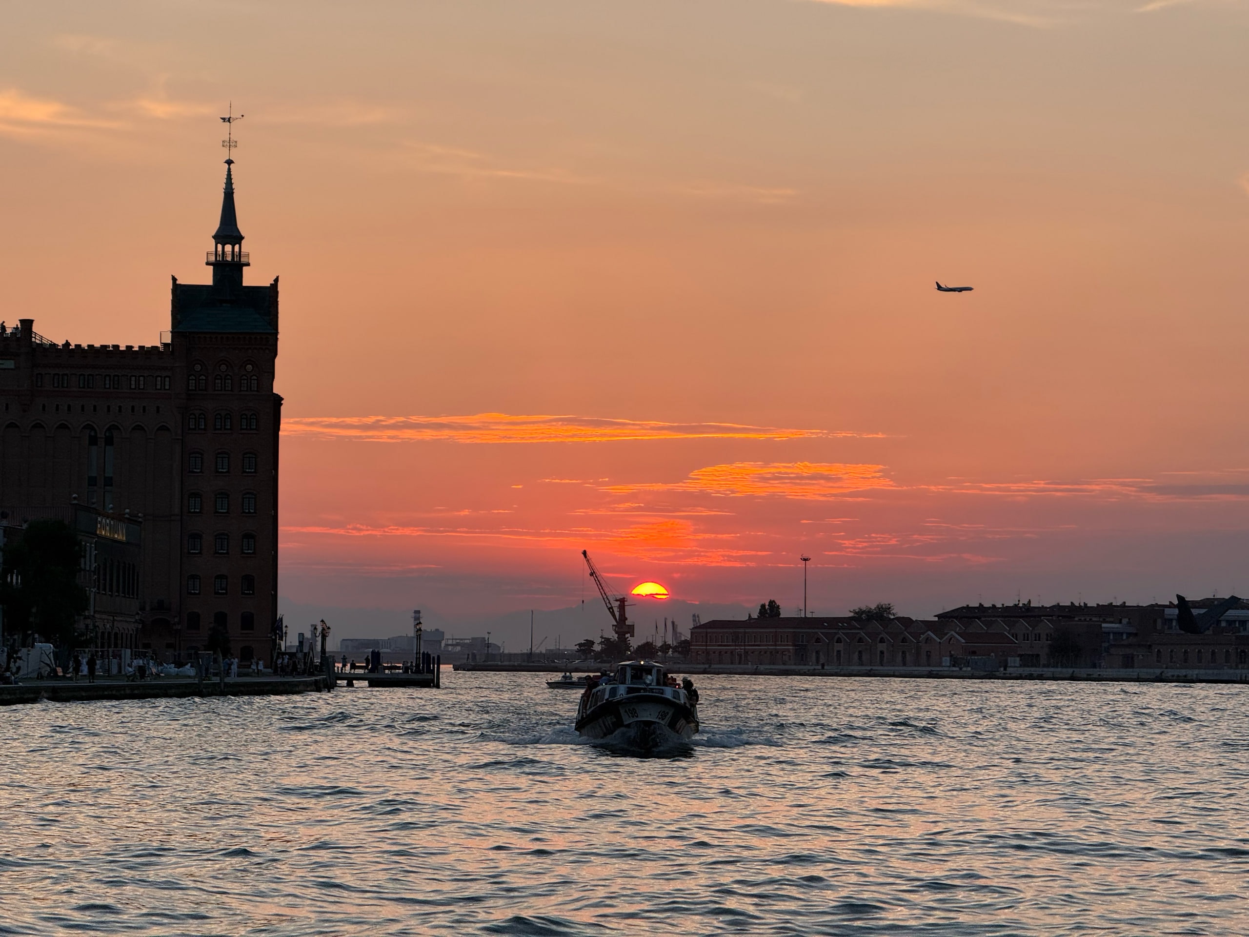 The Molino Stucky tower in silhouette against a low sun over the lagoon.
