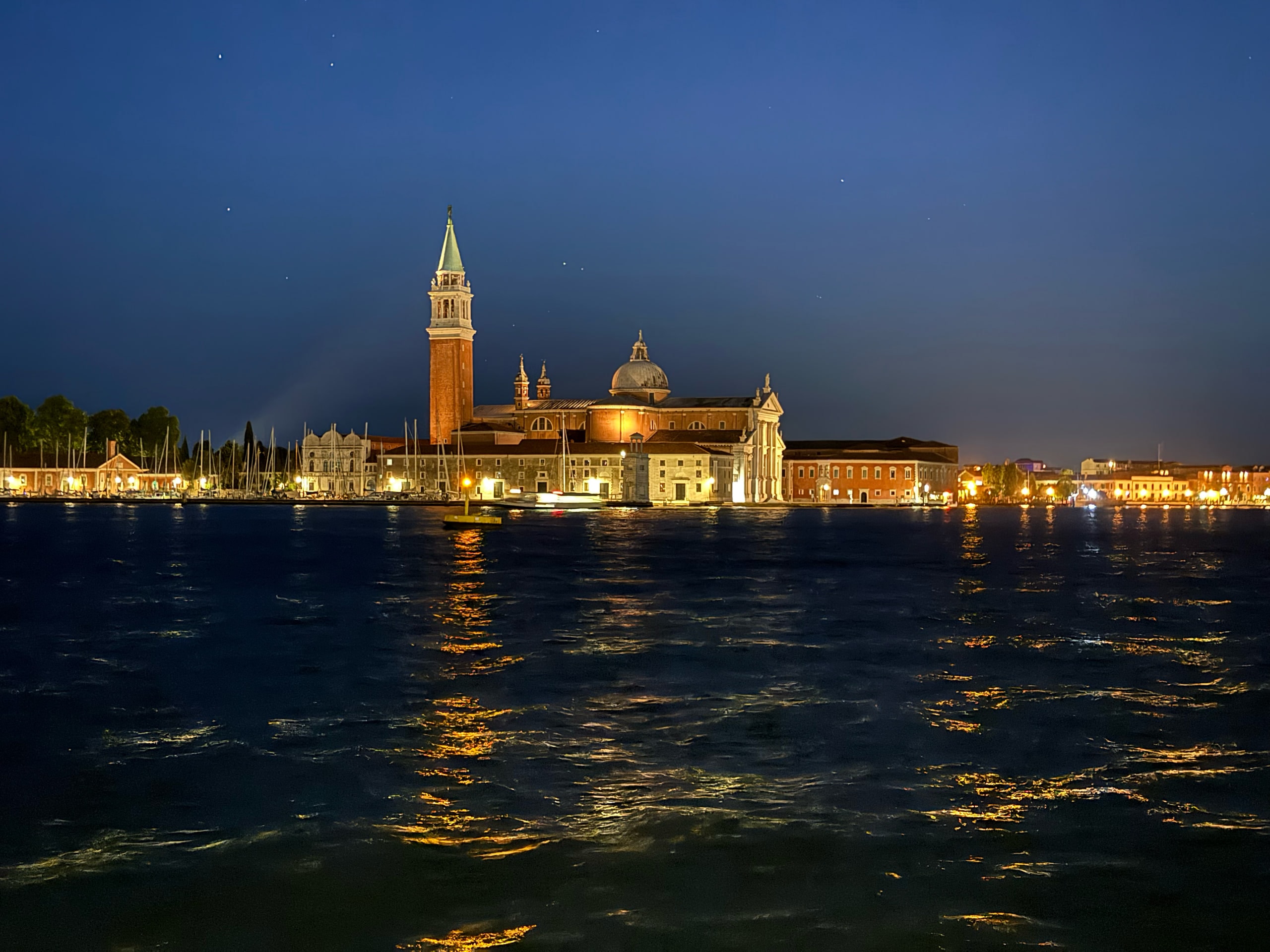 San Giorgio Maggiore across the water at blue hour, its lights doubled in the lagoon.