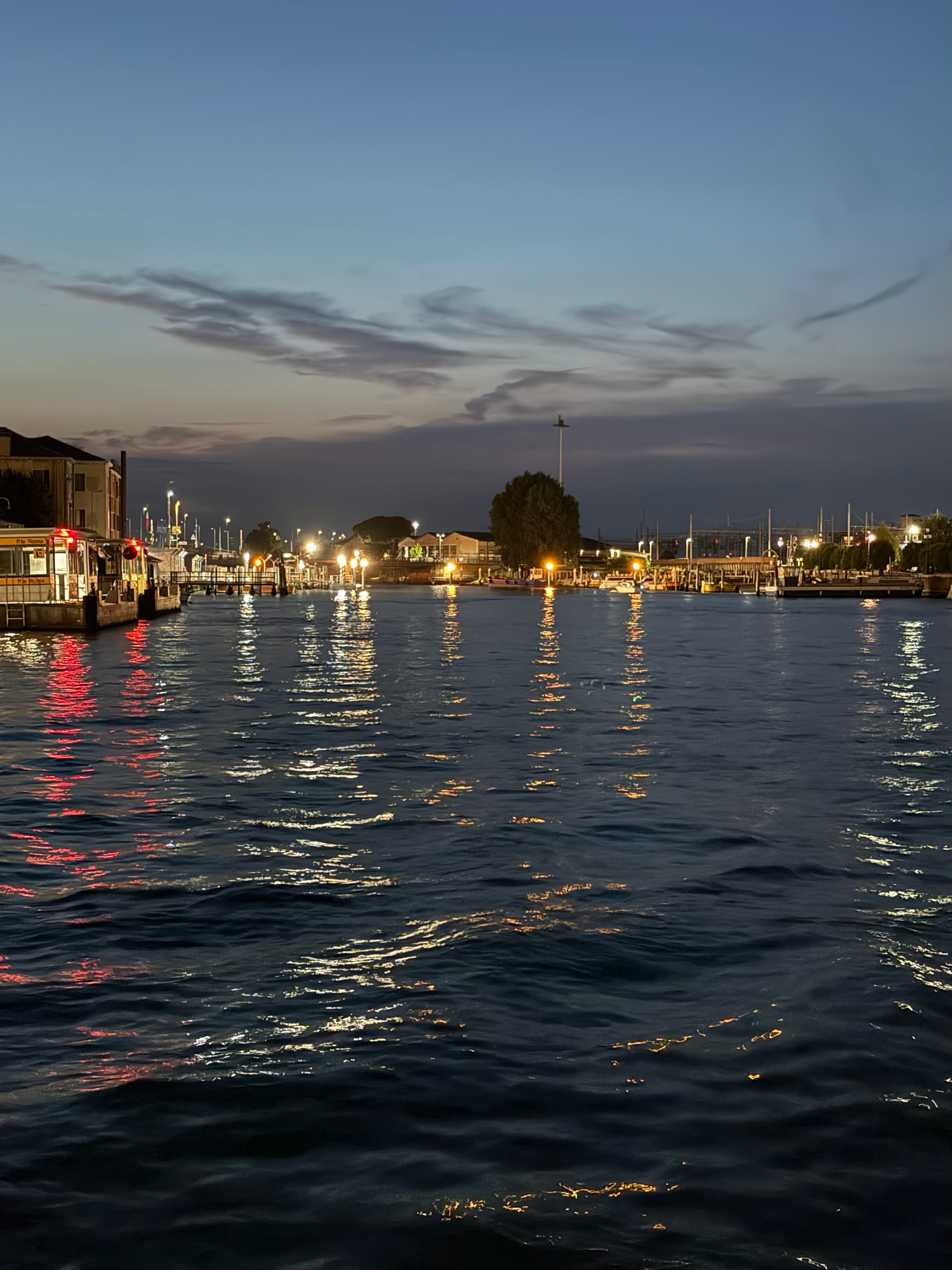 Low clouds over the Venetian Lagoon at blue hour, lights reflected on the water.