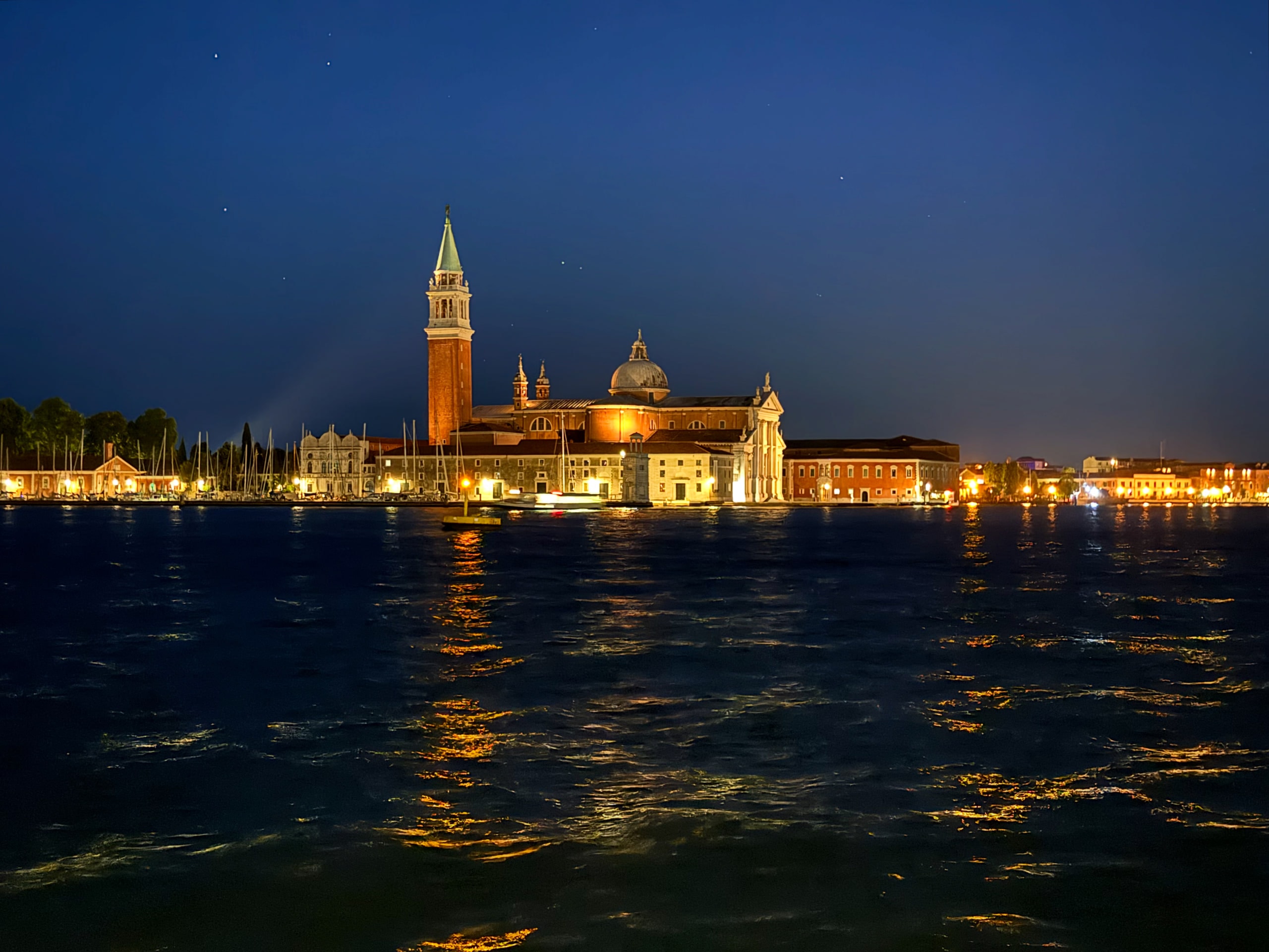 San Giorgio Maggiore illuminated across dark water beneath a starry sky.