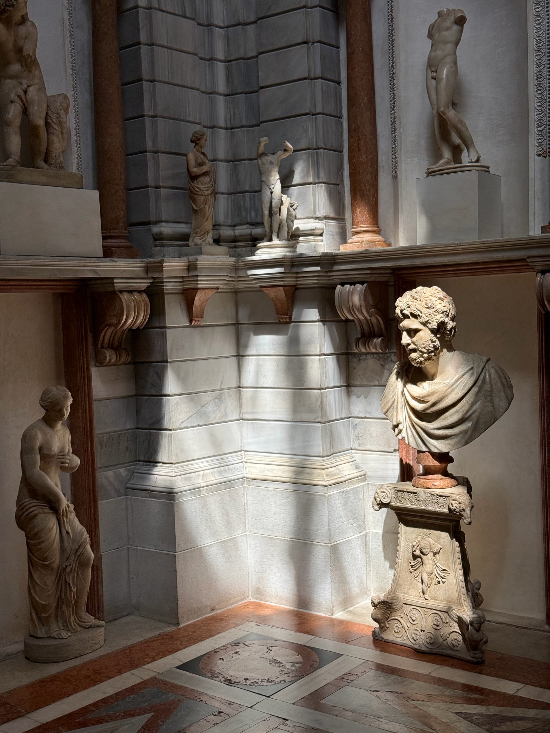 Marble figures lining an arcaded sculpture hall.