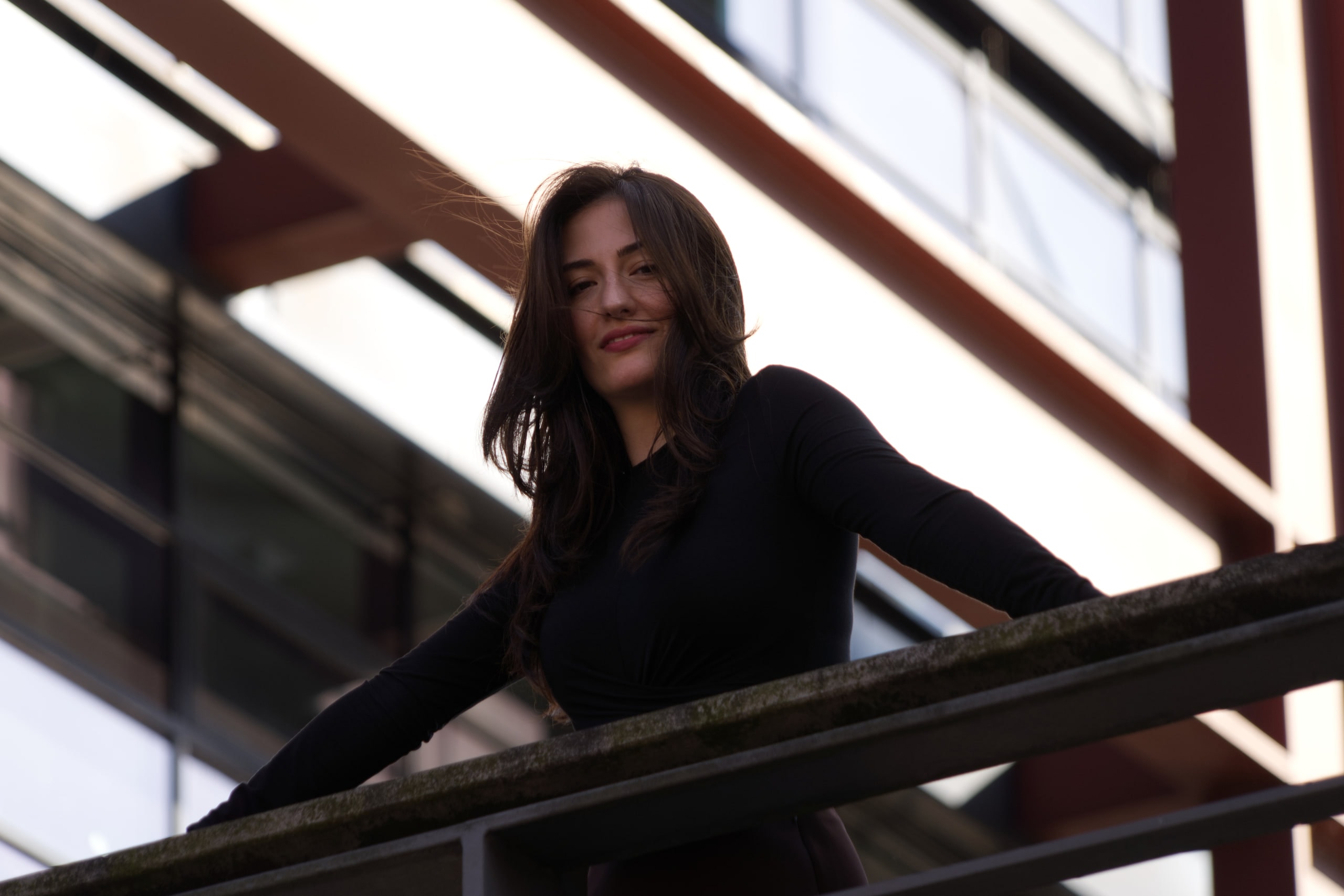 Breshna Hamid Khan leaning across a footbridge railing, her hair moving across her face.