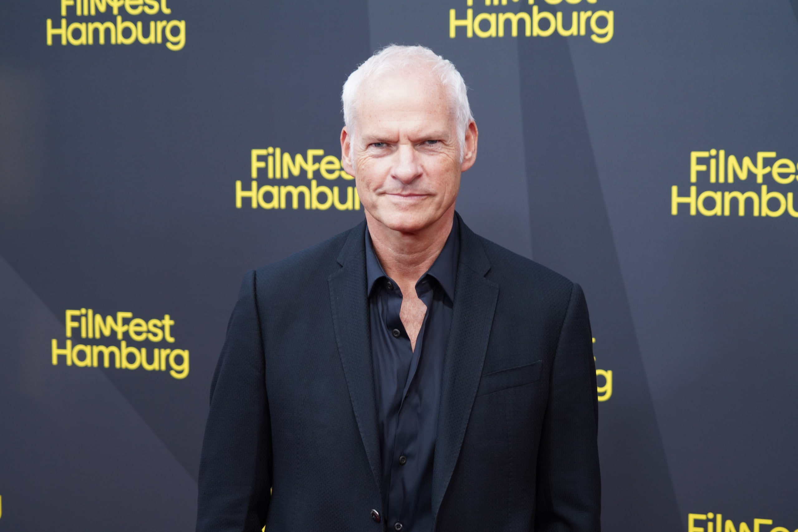 Martin McDonagh facing the camera in a dark jacket at the Filmfest Hamburg backdrop.