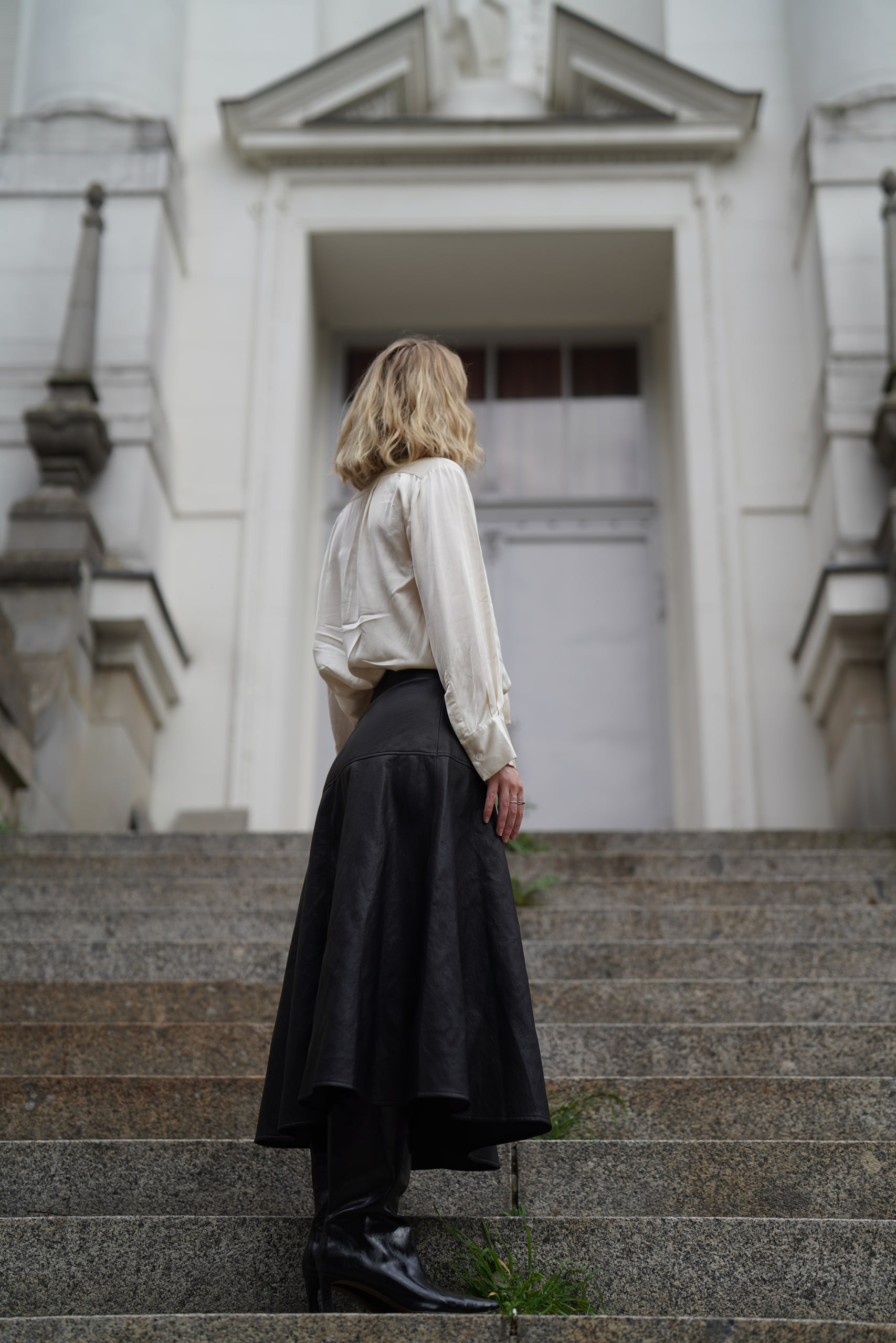 Sophia Repp seen from behind on stone steps leading to a white doorway.