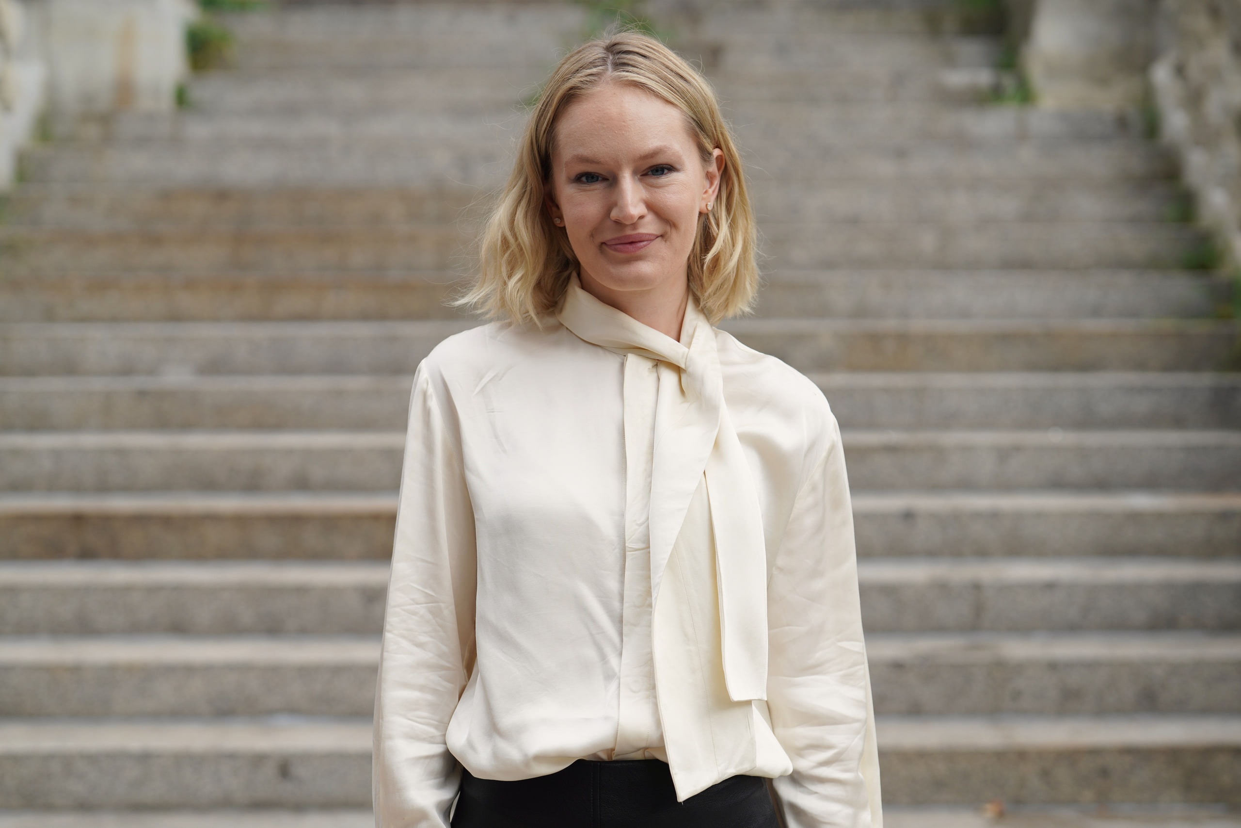 Sophia Repp meeting the camera's gaze in front of broad stone steps, wearing a cream blouse.