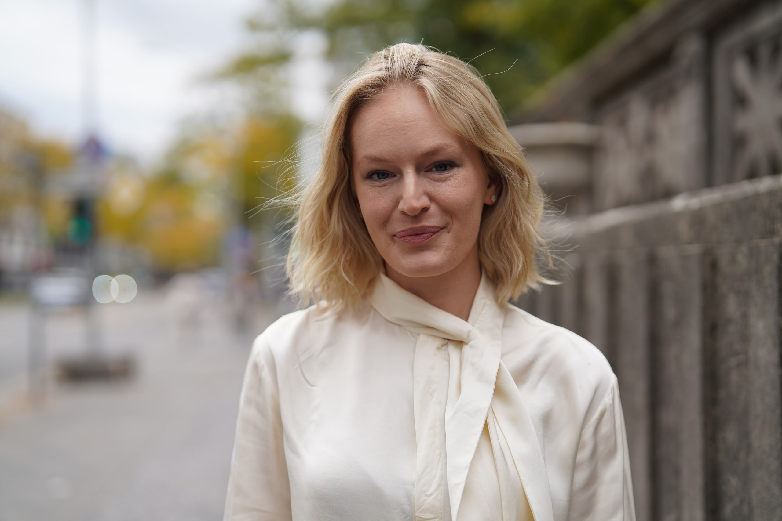 Close portrait of Sophia Repp beside a stone wall, with a Berlin street softly blurred behind her.