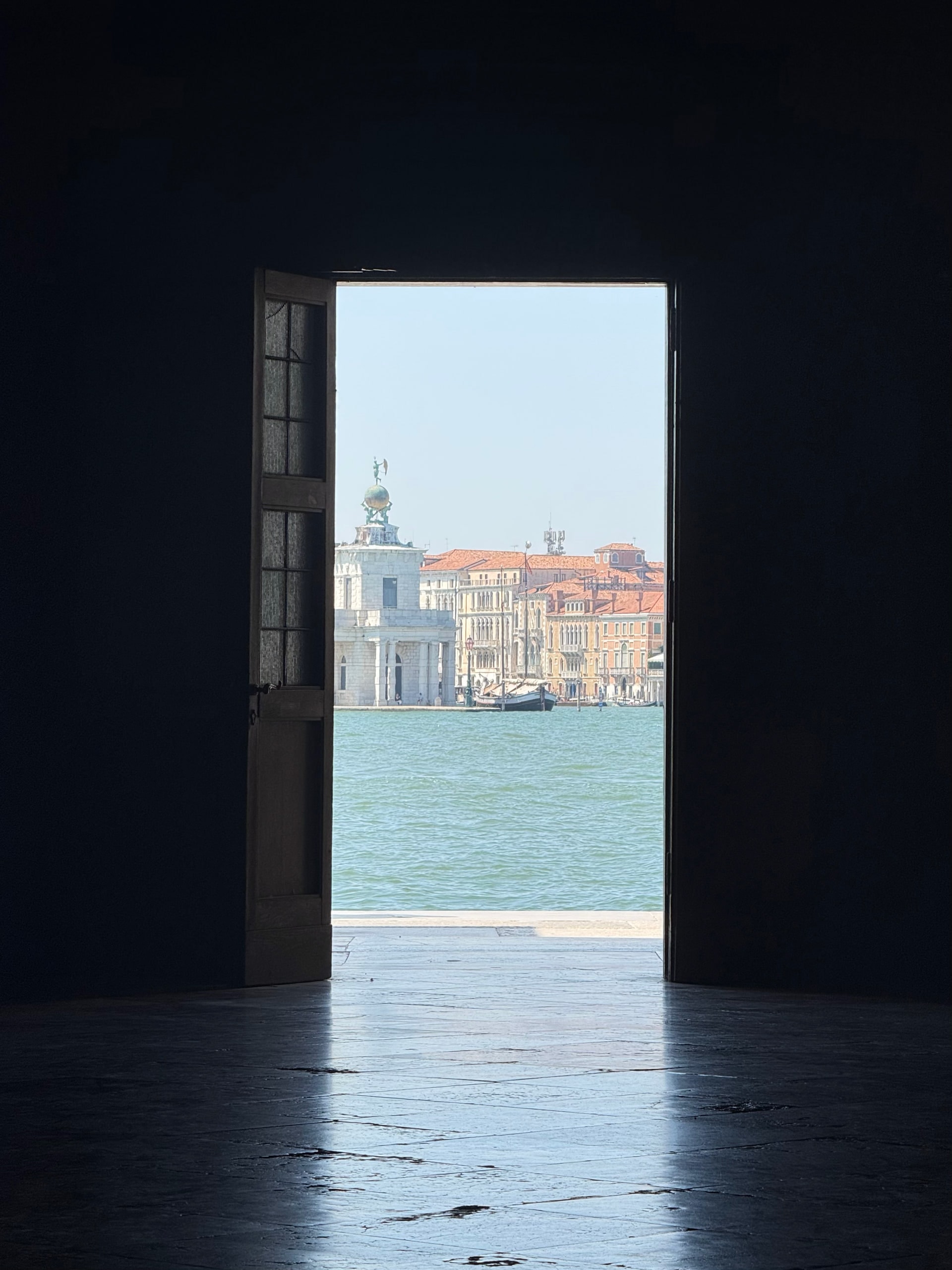 A bright view across the lagoon framed by a dark open doorway.